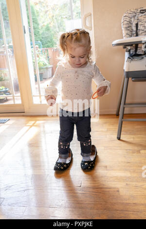 Almost 2 year old girl trying to walk in her mother's shoes. Stock Photo