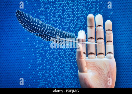 Articulated wooden hand delicately holding a bird feather on a mottled blue background Stock Photo