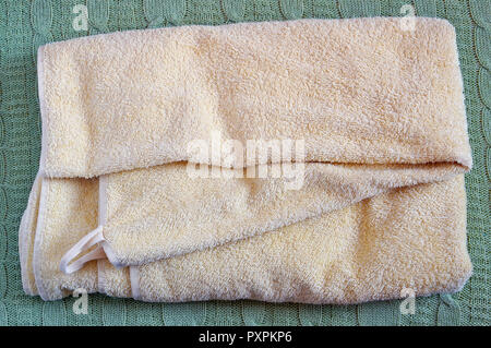 Terry yellow dry clean bath towel lie on a wool knitted bed coverlet Stock Photo