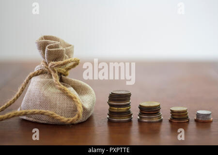 Money bag and Coin stacks on a wooden table Stock Photo