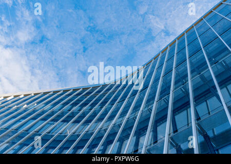 Curved facade of modern glass blue building with sky background. Stock Photo