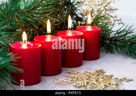 four red burning advent candles and a fir branch on a light background Stock Photo