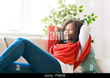 Attractive black young woman relaxing on a sofa at home Stock Photo