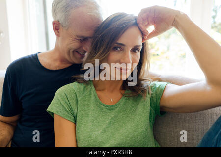 Portrait of happy mature couple sitting on couch at home Stock Photo
