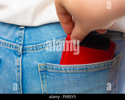 Close-up of a the hand of thief stealing the red wallet to a woman. Stock Photo