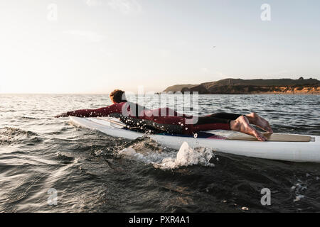 Young man on paddleboard at sunset Stock Photo