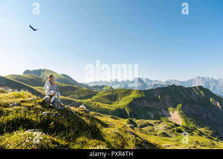 Germany, Bavaria, Oberstdorf, mother and little daughter on a hike in the mountains having a break looking at view Stock Photo