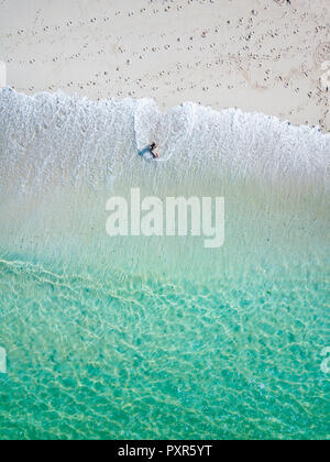 Indonesia, Bali, Young woman sitting on seashore Stock Photo