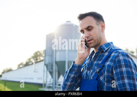 Farmer talking on cell phone on field Stock Photo