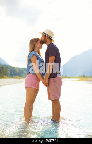 Young couple standing in water, kissing Stock Photo