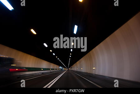 Motion blur driving a car at speed through a road tunnel Stock Photo
