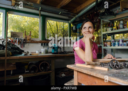 Smiling mature woman at workbench in her workshop Stock Photo