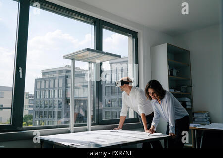 Two architects working on blueprints, man using VR glasses Stock Photo