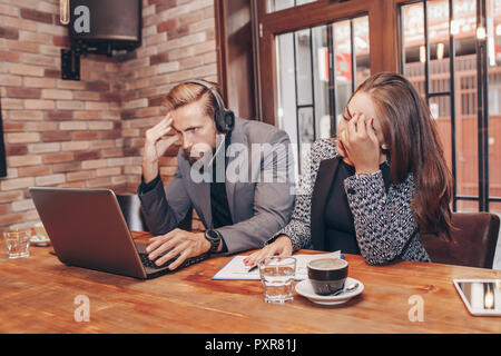 Stressed angry business man and woman with laptop looking at it sitting at table screaming at computer. Negative emotions in office life. Problems at  Stock Photo