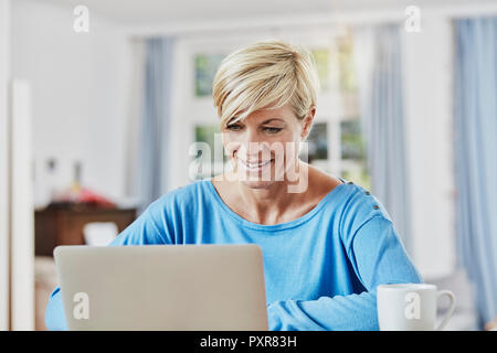 Woman using laptop at home Stock Photo