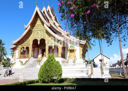 Two visitors leave the Ho Pha Bang temple at the royal palace in Luang Prabang,  Laos Stock Photo