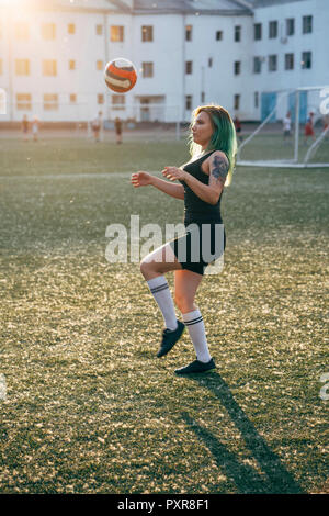 Young woman playing football on football ground balancing the ball Stock Photo