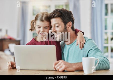 Father and daughter using laptop at home Stock Photo