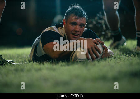 Rugby player scores a touchdown during the game. Rugby player making a touch down during the match. Stock Photo