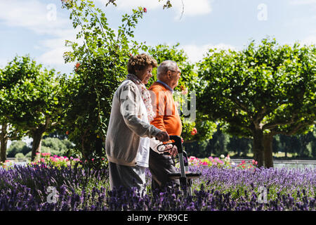 Senior couple walking in park, woman using wheeled walker Stock Photo