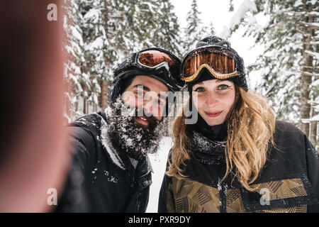 Selfie of smiling couple in skiwear in winter forest Stock Photo