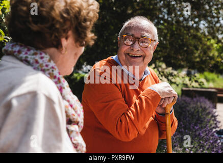 Senior couple sitting on bench in a park, talking Stock Photo