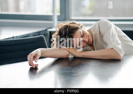 Tired businesswoman sleeping on her desk Stock Photo