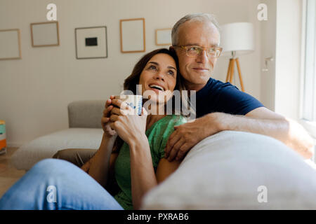 Happy mature couple sitting on couch at home Stock Photo
