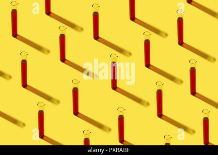 Row of test tubes with red liquid, yellow background Stock Photo