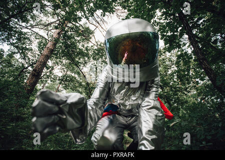 Spaceman exploring nature, examining plants in forest Stock Photo