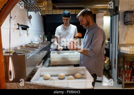 Two men with raw dough in boxes in kitchen of a pizzeria Stock Photo