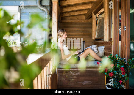 Smiling woman on balcony using laptop Stock Photo