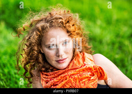 Portrait of freckled young woman with curly red hair wearing orange scarf Stock Photo