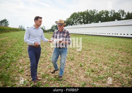 Farmer and businessman discussing data from clipboard on the field Stock Photo