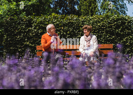 Senior couple sitting on bench in a park, talking Stock Photo