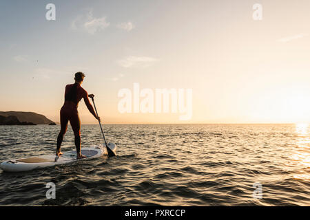 Young man on paddleboard at sunset Stock Photo