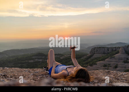 Spain, Catalonia, Sant Llorenc del Munt i l'Obac, woman taking pictures in the mountains with her smartphone Stock Photo