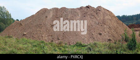 A large pile of construction sand  on forest grassy site. Panoramic collage from several outdoor shots Stock Photo