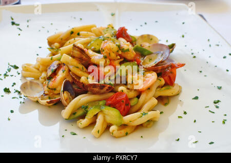 Shrimps squids and other seafood in salad with pasta on a white ceramic plate in an Italian restaurant. Food photo  in the style of phone snapshot Stock Photo