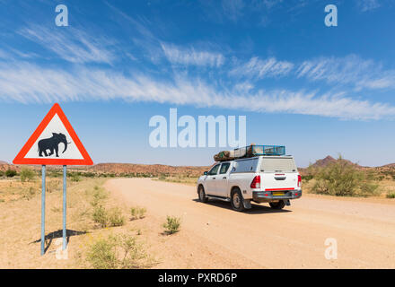 Namibia, Erongo Region, off-road vehicle on sand track, deer crossing sign with elephant Stock Photo