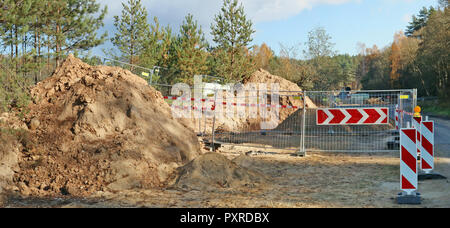 A large pile of sand and steel fence with road sign in  a autumn forest  construction site. Panoramic collage from several outdoor sunny October day s Stock Photo