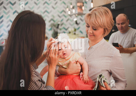 Family dinner. Family receives guests, a festive meeting. Mom and adult daughter holding baby granddaughter Stock Photo