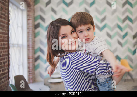 Family dinner. Family receives guests, a festive meeting. Young mom holding son on hands Stock Photo