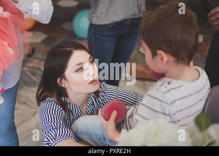 Family dinner. Family receives guests, a festive meeting. Young mom holding son on hands Stock Photo