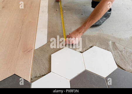 Male worker installing new wooden laminate flooring on a warm film floor. infrared floor heating system under laminate floor Stock Photo