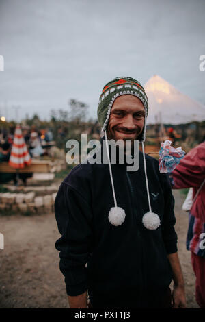 Photo of smiling man who is wearing a peruvian wool cap to keep warm at a outdoors music festival Stock Photo