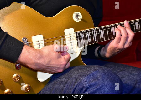 Man playing a gold top electric guitar with P90 pickups. Hands playing a chord. Gibson Les Paul type model. Stock Photo