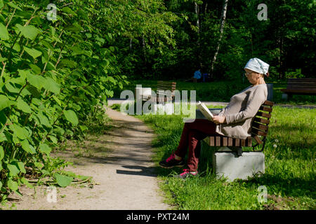 Moscow, Russia, 11.06.2018, Old lady reading a book at the bench Stock Photo