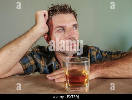 isolated portrait of young drunk addict and alcoholic man drinking whiskey glass intoxicated looking wasted resisting temptation to his alcohol addict Stock Photo