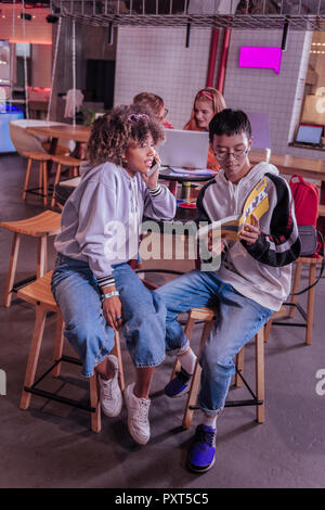 Clever international teenager helping his classmate with task Stock Photo
